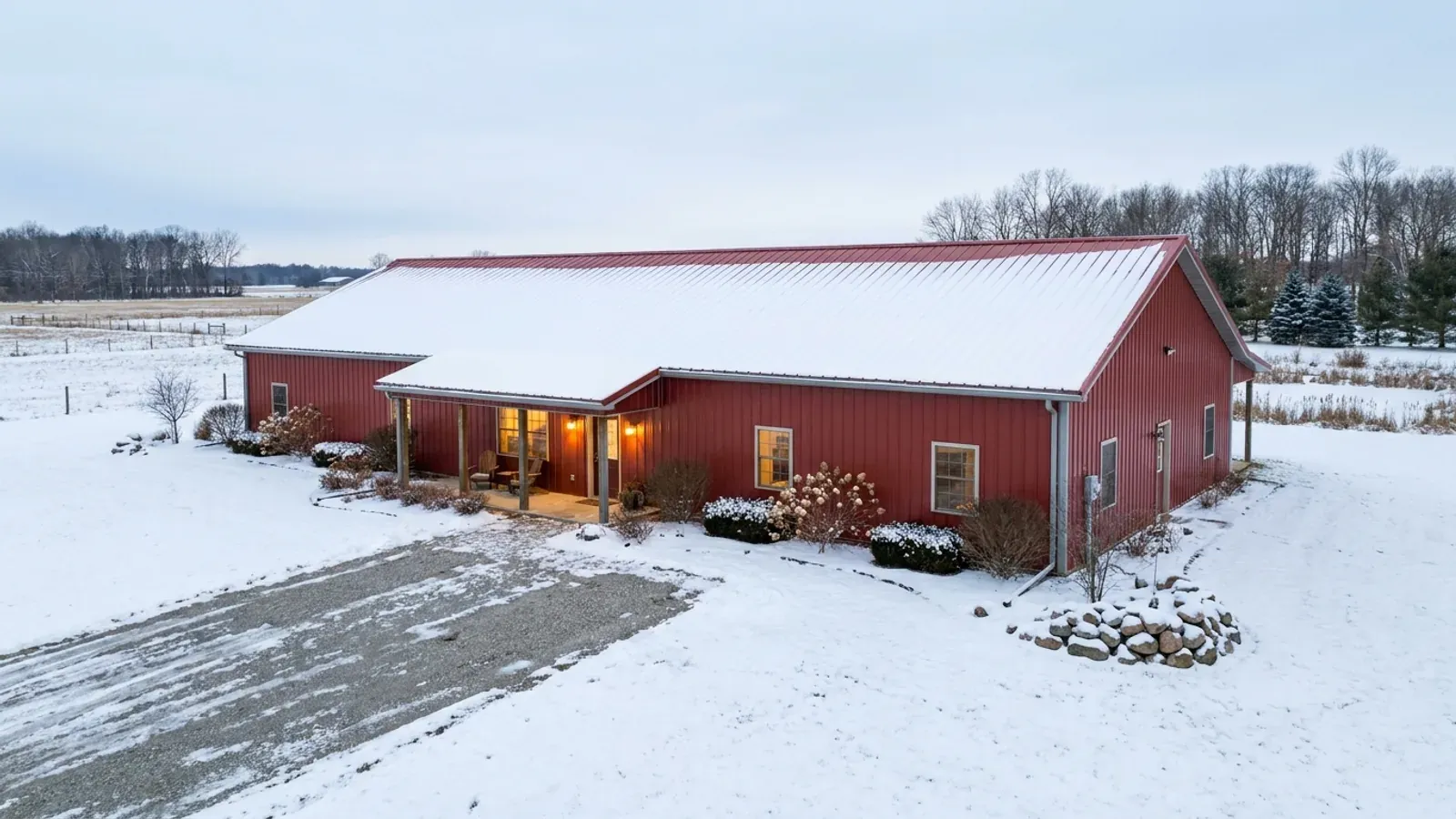 A completed single-story barndominium in winter with a long, low snow-covered roofline and no upper-level windows.